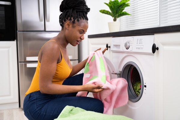  Woman looking frustrated at clothes out of the dryer.