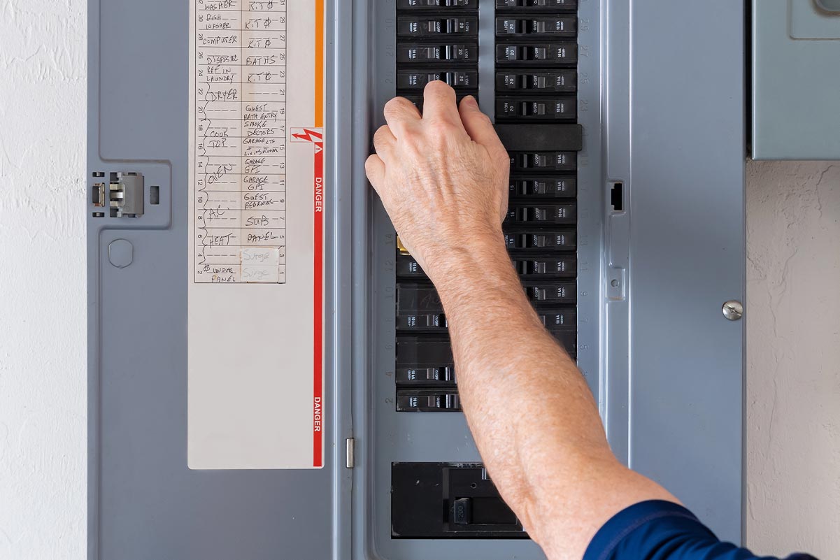 An individual turning off a circuit breaker.