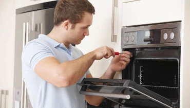 Appliance repair tech servicing an oven