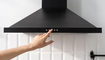 Close up of hand pressing buttons on kitchen hood vent.