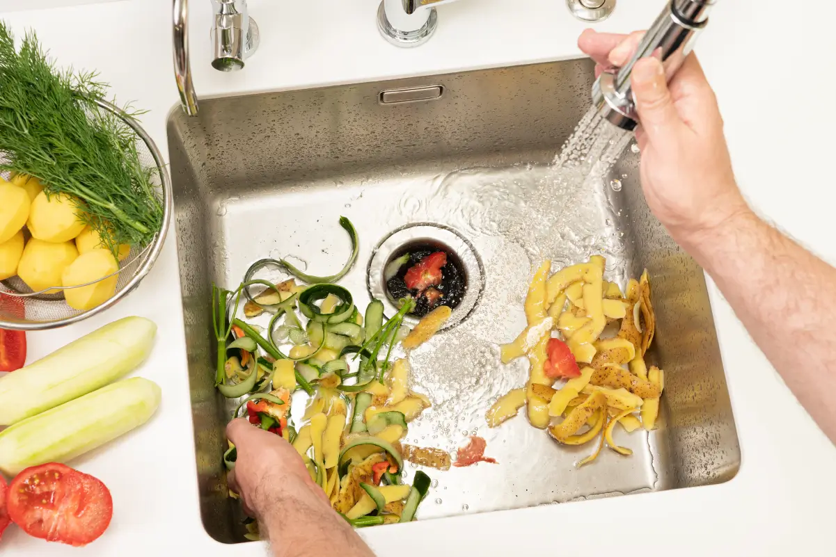 Kitchen sink filled with discarded food from a clogged garbage disposal.