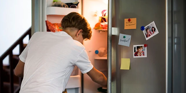 man looking in a chrome refrigerator