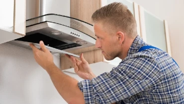 Technician repairing exhaust fan over cooktop