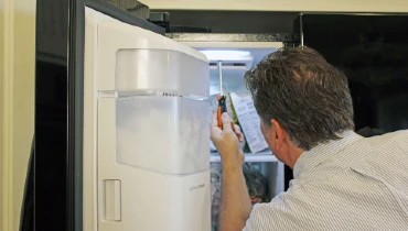 Appliance repair tech servicing a refrigerator