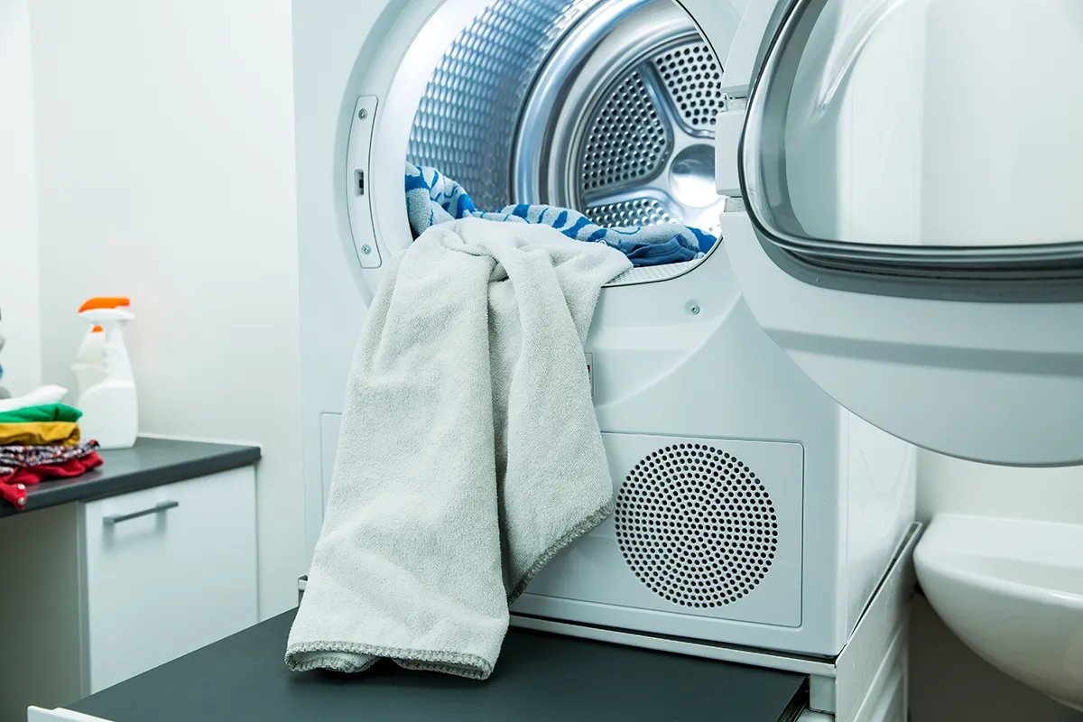 An open front load dryer with a sheet coming out.