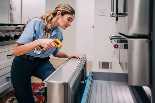 Mr. Appliance technician using an infrared thermometer to test the internal temperature of a freezer drawer.