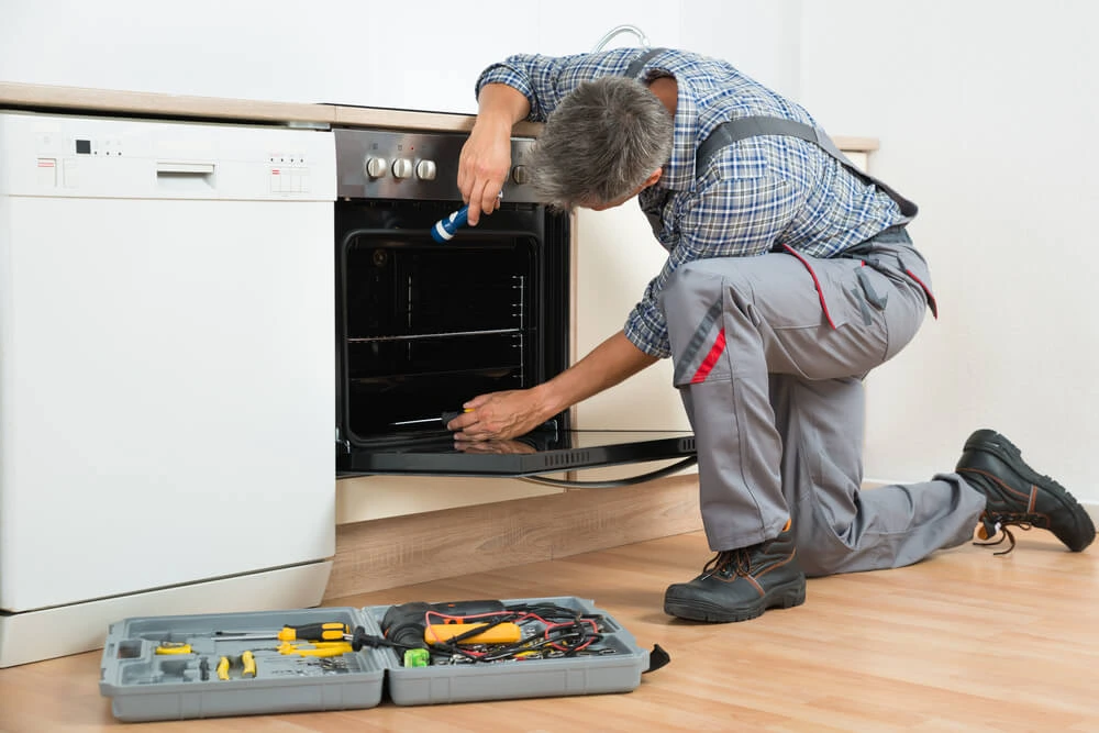 Appliance repair tech servicing an oven