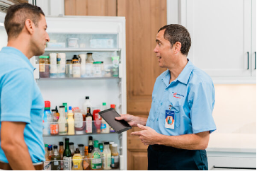 Mr. Appliance service professional and Issaquah homeowner in kitchen discussing refrigerator repairs