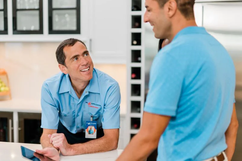 Mr. Appliance tech discussing GE appliance repair services with couple