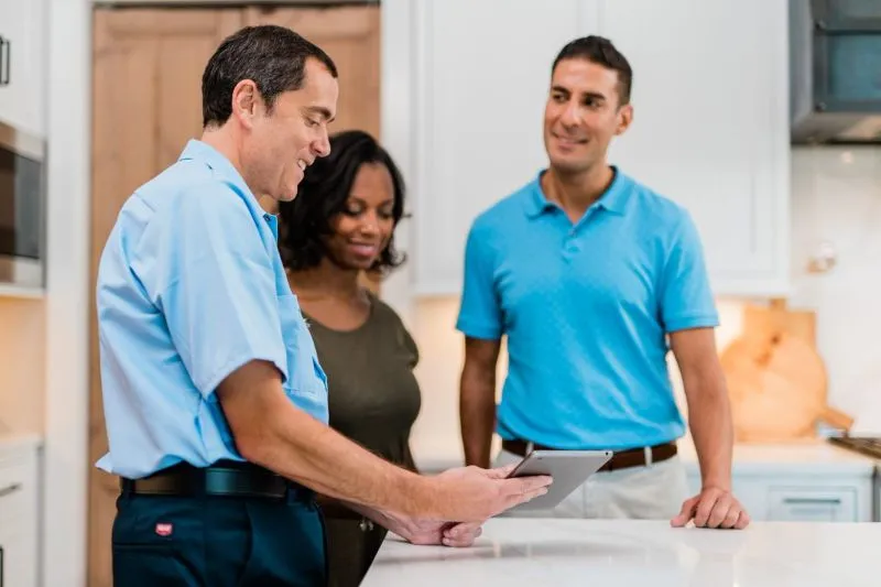 Mr. Appliance tech discussing Maytag appliance repair services with couple 