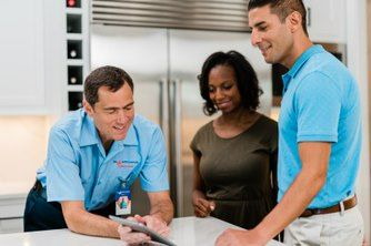 A Mr. Appliance dryer tech reviewing repair details with happy customers