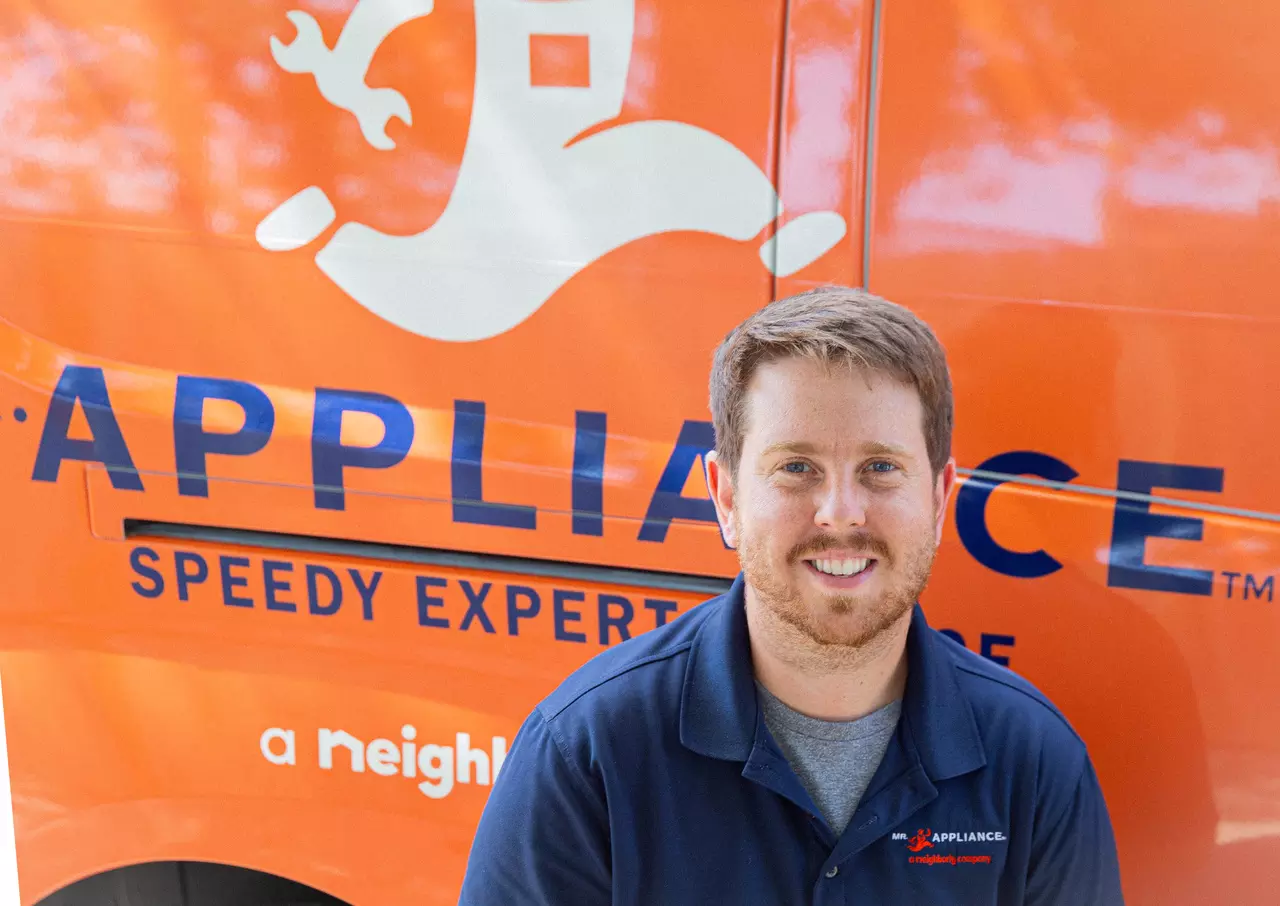 Mr. Appliance technician in front of marked business van