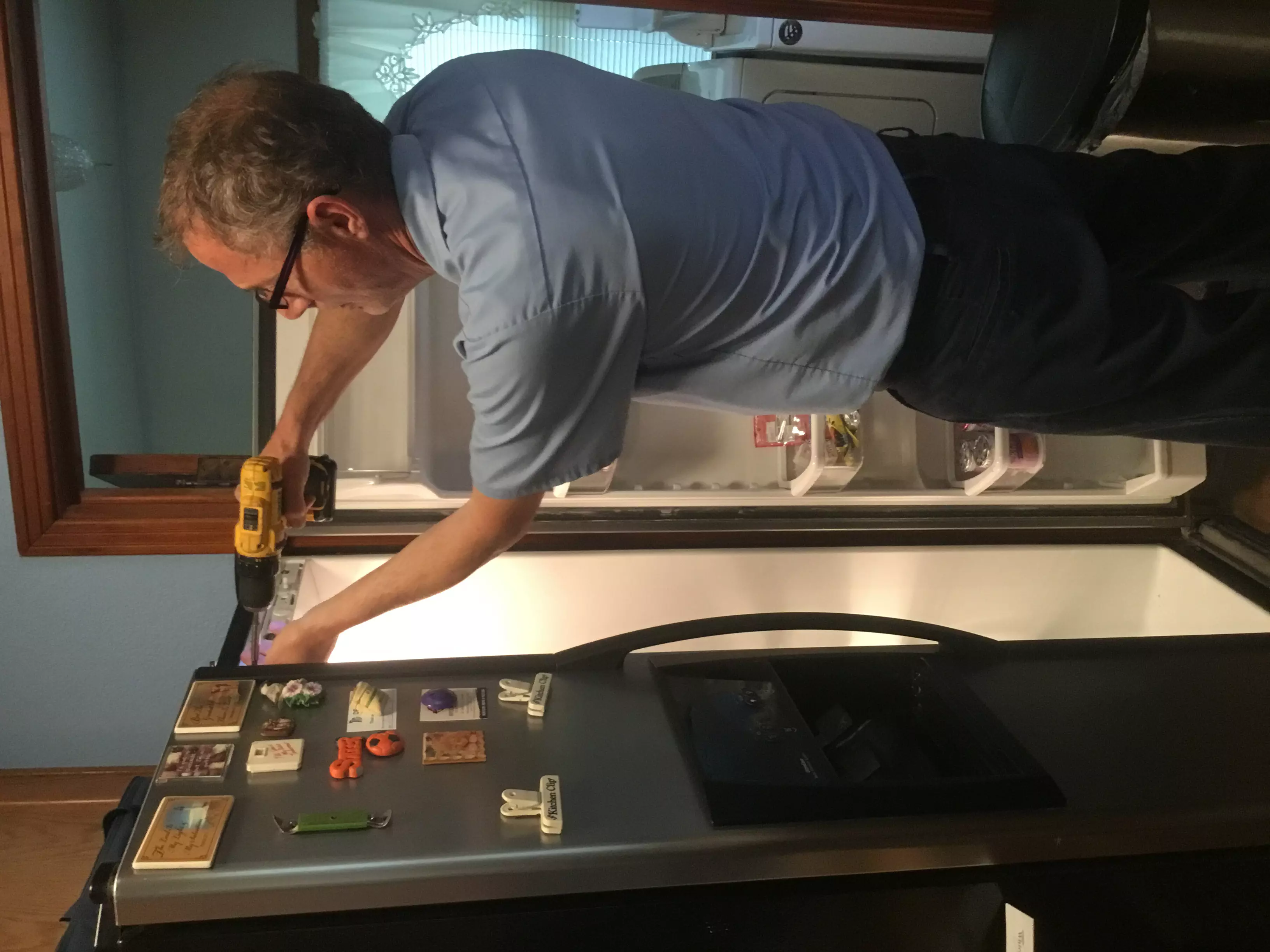 Mr. Appliance technician repairing fridge in Derby home