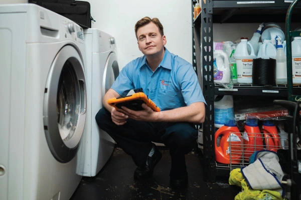 Service professional kneeling next to a washer.